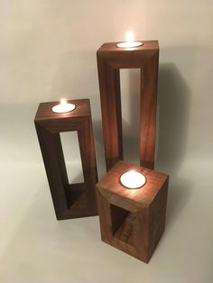 three wooden cubes with lit candles in them