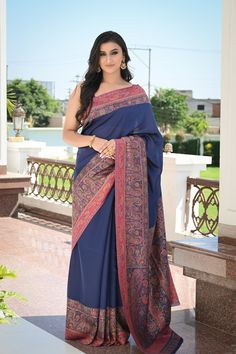 Navy Blue Kani Jamawar saree in silk fabric is accentuated with Kani weaving over the borders and pallu in traditional motifs like paisleys and flowers. Some amount of zari woven with the threads adds a touch of shine. It is accompanied with Kani Jamawar blouse piece in pink colour. The design inspiration for this Pashmina Silk saree is drawn from the heritage weaves of ancient Pashmina shawls from our history that dates back to the Mughal era.  Colour: Navy Blue  Craft: Kani Weave Fabric: Silk Elegant Blue Raw Silk Pre-draped Saree, Blue Silk Traditional Wear With Printed Border, Blue Banarasi Silk Traditional Wear With Printed Border, Pre-draped Katan Silk Saree With Printed Border, Elegant Blue Handloom Pre-draped Saree, Blue Saree With Printed Border For Eid, Blue Pre-draped Saree With Printed Border, Blue Raw Silk Pre-draped Saree For Eid, Elegant Silk Pashmina Shawl With Cutdana