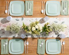 an overhead view of a table set with place settings and flowers on the napkins