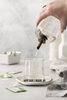 a person pouring water into a glass on top of a table