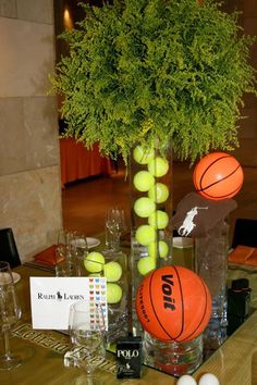 an arrangement of tennis balls and basketballs in a vase on a dining room table