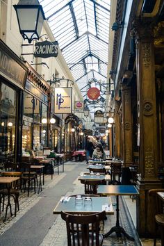 the inside of a restaurant with tables and chairs in front of it's glass roof