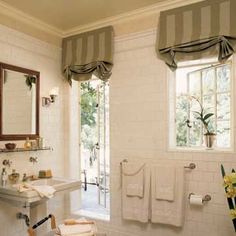 a white bathroom with two sinks and towels on the rack