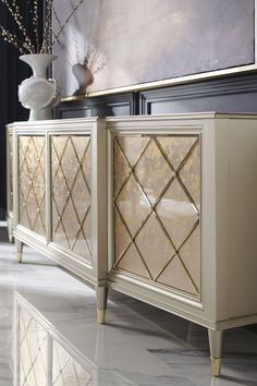 a white and gold sideboard sitting on top of a floor next to a vase