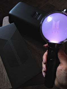 a person holding a magnifying glass on top of a wooden table next to a black box