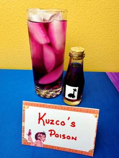 a table with a sign and a glass filled with liquid next to a bottle of kozo's poison