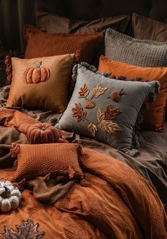 a bed covered in lots of pillows and pumpkins on top of it's covers