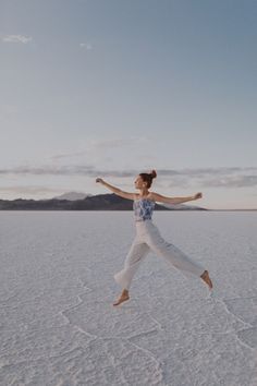 a woman jumping in the air on top of a salt flat