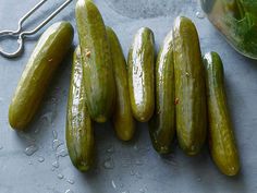 several cucumbers on a table next to a jar of lettuce