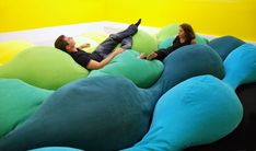 two people laying on bean bag chairs in a yellow and green room with black flooring