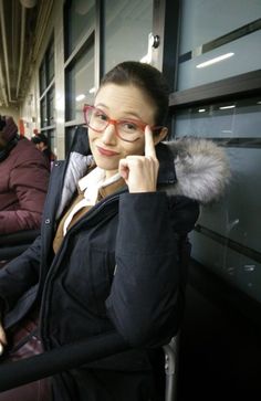 a woman with glasses is sitting on a bus