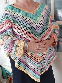 an older woman wearing a multicolored crocheted ponchy with her hands on her hip