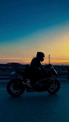 a person riding on the back of a motorcycle down a highway at sunset or dawn