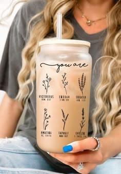 a woman holding up a drink with the names you are on it and herbs in it