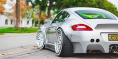 the back end of a silver sports car with green stickers on it's bumper