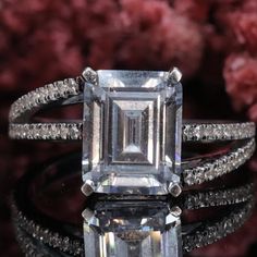 an emerald cut diamond ring surrounded by diamonds