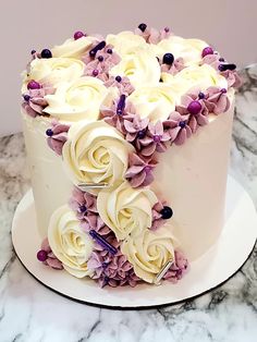 a cake with white frosting and purple flowers