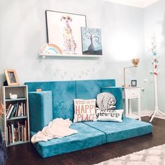 a living room with a blue couch and bookshelf on the floor next to a white rug