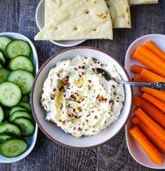 hummus, carrots, cucumbers and pita bread on a table