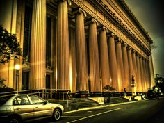 a car parked in front of a tall building with columns on it's side