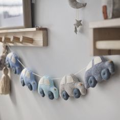 a baby mobile with cars hanging from it's side on a wall next to a window