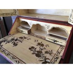 an ornately painted wooden cabinet with drawers and shelves on the bottom shelf is shown