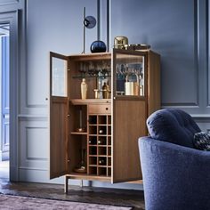 a living room filled with furniture and a wine cabinet next to a blue chair in front of a doorway