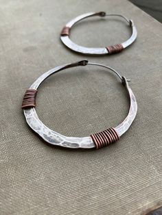 "Substantial 10 gauge solid Sterling silver has been hammered into 2\" big hoops and wrapped with genuine copper. ** listing is for ONE pair of hoops Despite their thickness, these earrings are lightweight and easy on the ear. 20 gauge Sterling earwires. Too small? I offer a larger version here: https://etsy.me/2JukcGm Handmade in NY PLEASE NOTE: For sanitary and hygienic reasons, all earring sales are FINAL. ALL unauthorized returns will be subject to a 25% restock fee. Every item comes careful Small Hammered Metal Hoop Earrings, Artisan Metal Hoop Jewelry, Hammered Metal Hoop Earrings, Small Metal Hoop Earrings With Soldered Detail, Small Hoop Metal Earrings With Soldered Details, Small Hoop Hand Forged Metal Jewelry, Adjustable Oxidized Finish Hoop Earrings, Adjustable Oxidized Hoop Earrings, Hammered Metal Hoop Jewelry