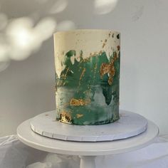 a green and white cake sitting on top of a white table next to a white wall