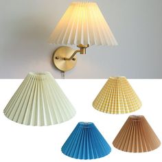 four different shades of paper lamps on a white wall and one is blue, the other is yellow