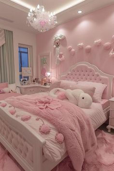 a bedroom decorated in pink and white with teddy bears on the bed, chandelier