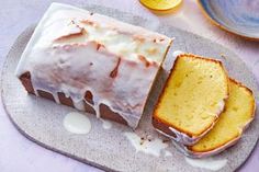 a loaf of lemon pound cake sitting on top of a plate next to two slices