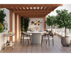 an outdoor dining area with potted plants on the wall and wooden flooring in front of it