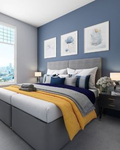 a bedroom with blue walls and gray bedding, two pictures on the wall above it