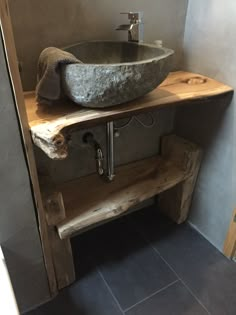 a bathroom with a stone sink and wooden shelf