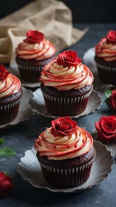 four cupcakes with frosting and red roses on them