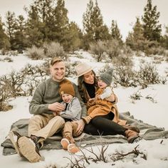 a man, woman and child sitting on a blanket in the snow