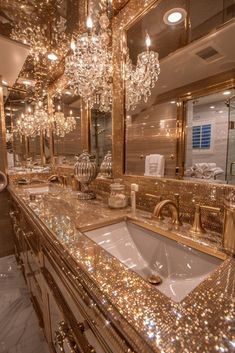 a fancy bathroom with gold fixtures and chandelier hanging from the ceiling, along with marble counter tops