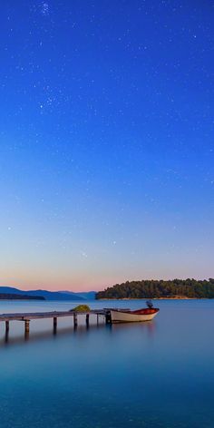 a boat sitting on top of a body of water under a sky filled with stars