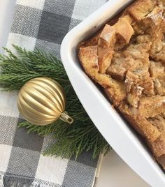 a casserole dish filled with bread and stuffing next to a christmas ornament