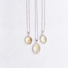 three necklaces with two different pendants hanging from the same chain on a white background