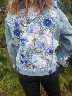 a woman wearing a jean jacket with blue flowers on it and lace detailing the back