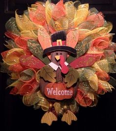 a wreath with a turkey wearing a top hat and holding a sign that says welcome