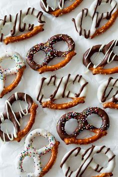 several pretzels with chocolate frosting and sprinkles are arranged on a sheet of paper