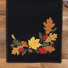 a black area rug with leaves and acorns on the border is sitting on a wooden floor