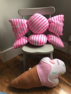 pink and white striped pillows stacked on top of an ice cream cone shaped pillow in front of a chair