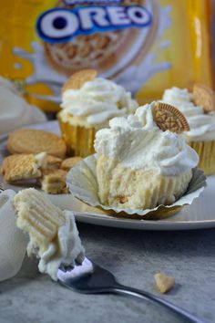 cupcakes with white frosting and oreo crackers on the plate next to them