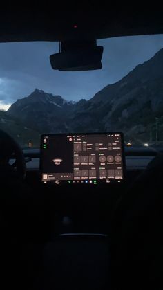 the dashboard of a car at night with mountains in the background and dark clouds overhead