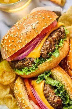 two hamburgers with lettuce, tomato and onion on a bed of chips