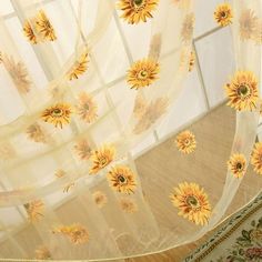 the sunflowers are hanging on the sheer curtain in the room with wood flooring